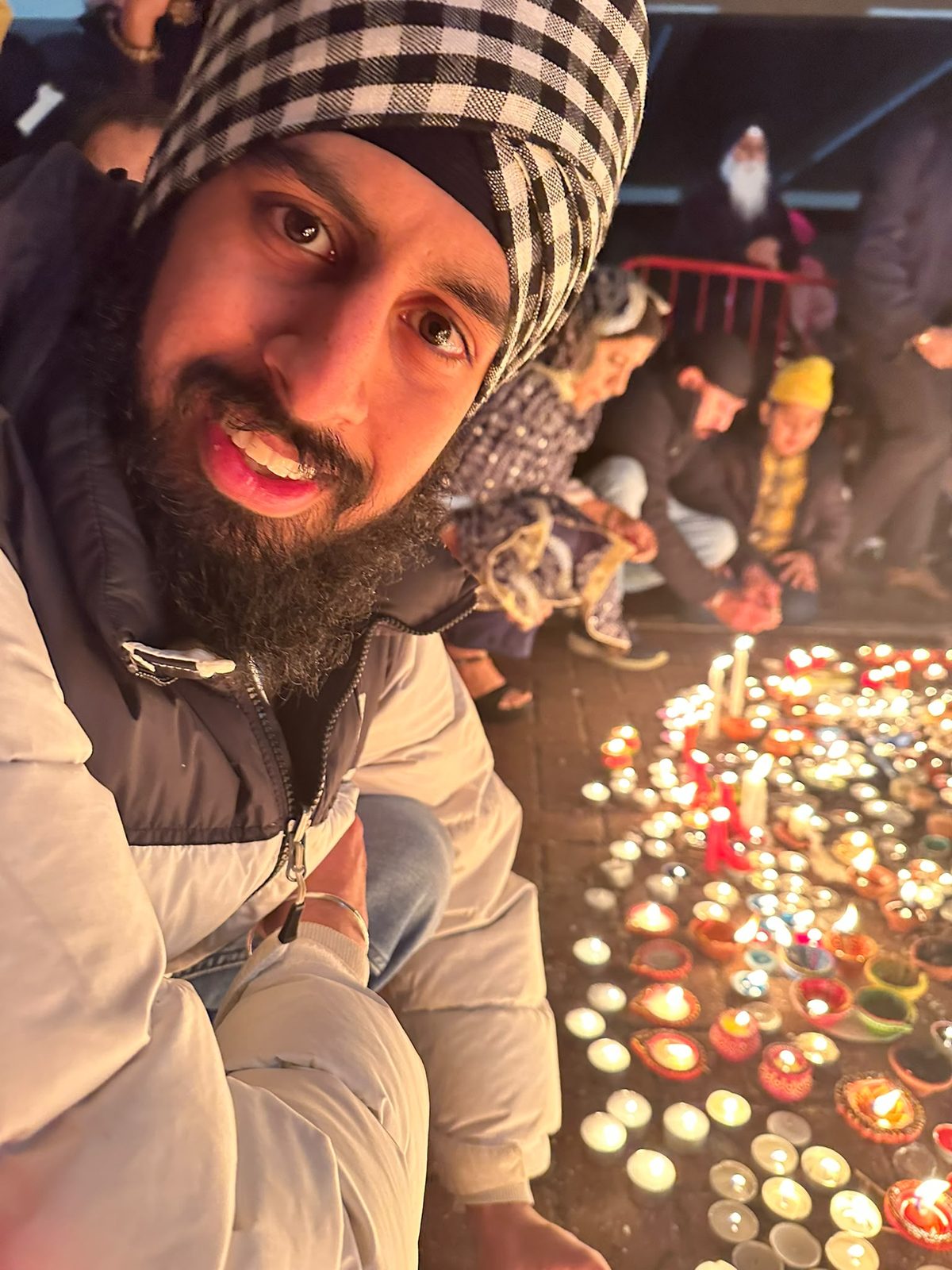 Nirmit smiling beside rows of lit candles