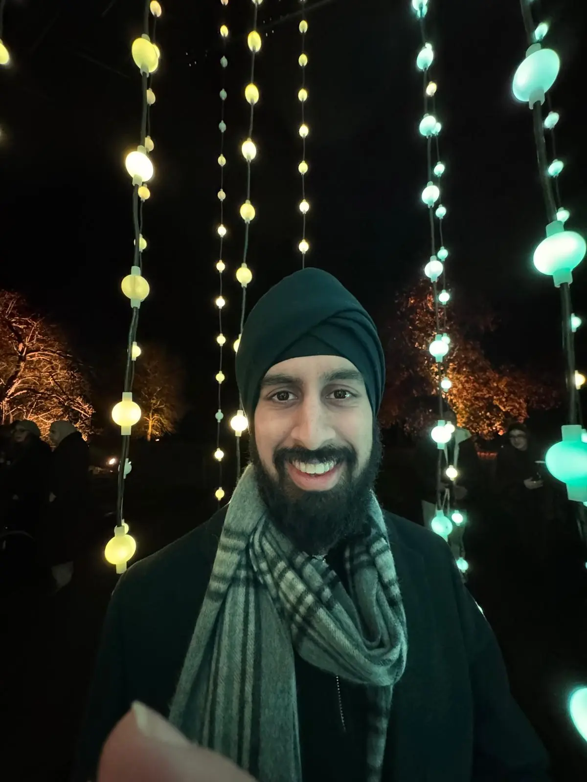 Nirmit smiling under strings of glowing lights at night