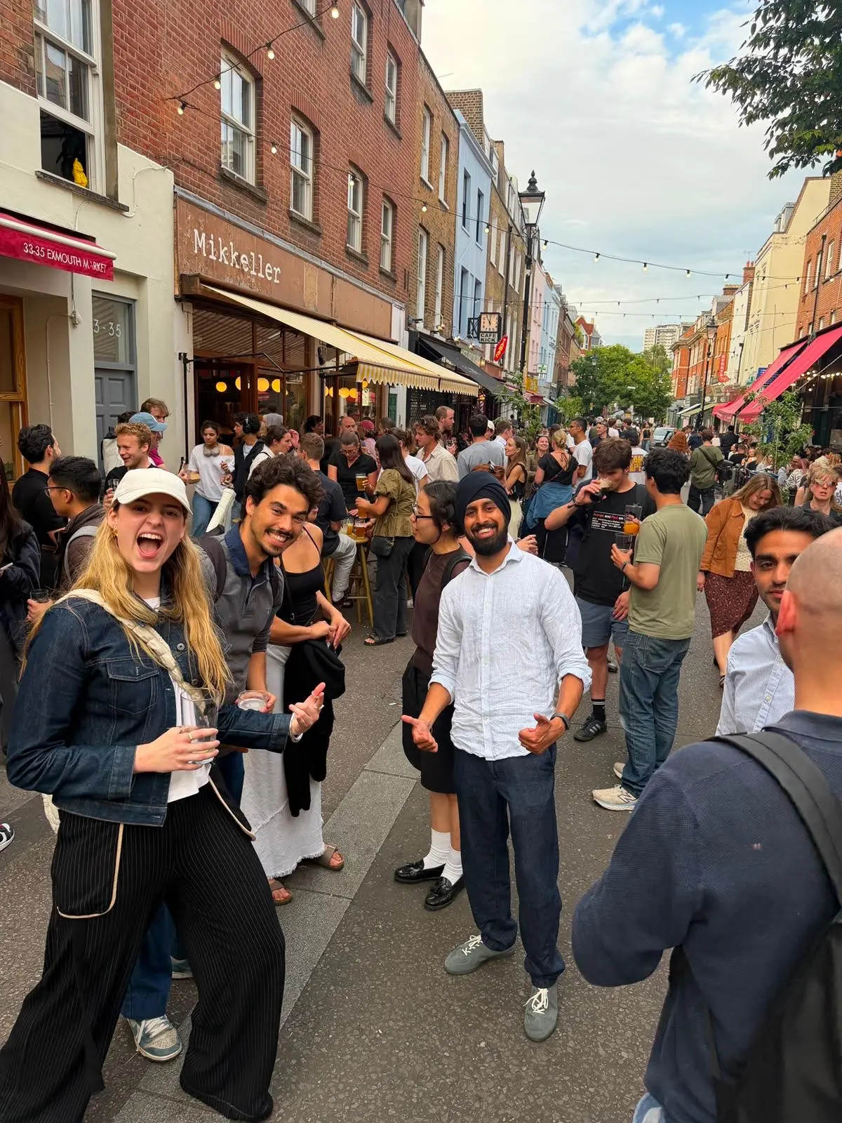 Nirmit giving a thumbs up among friends on a busy London street