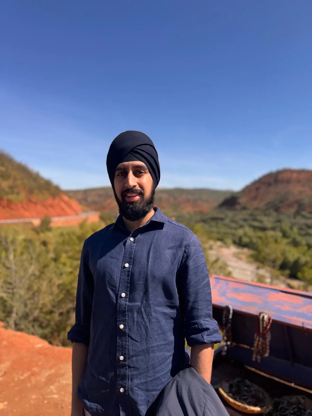 Nirmit in a blue shirt above a valley of red hills