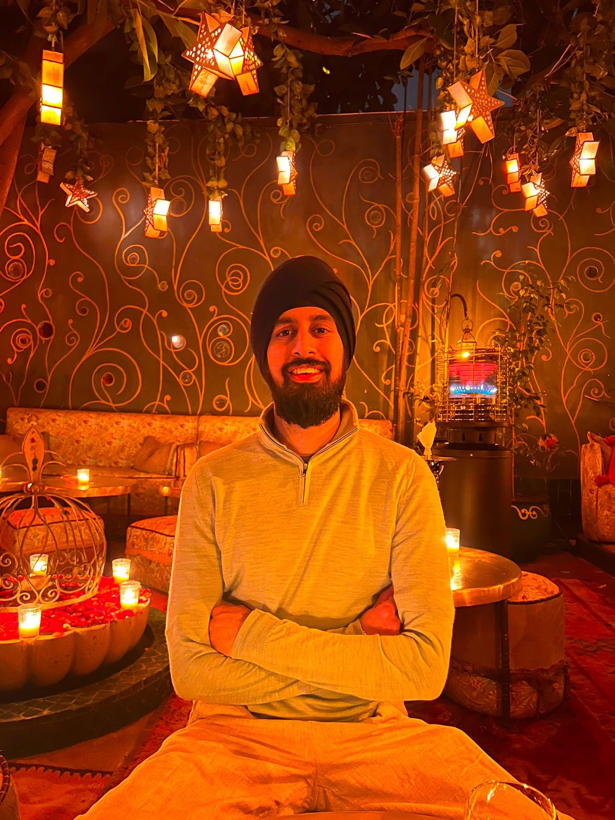 Nirmit sitting cross-armed, smiling, under warm lantern light